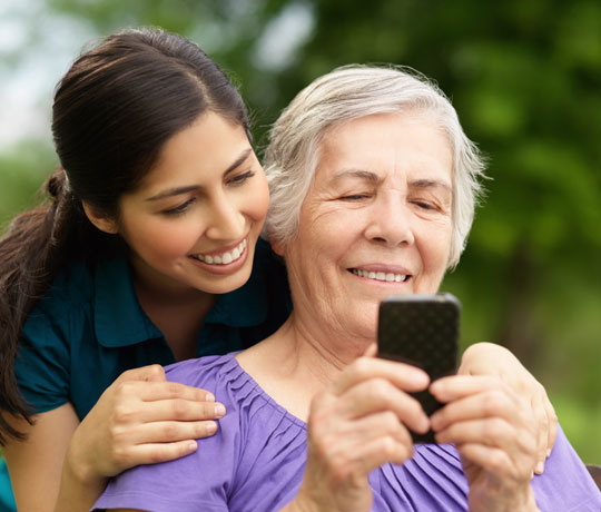 Smiling woman and daughter looking at mobile device