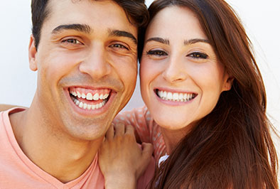 A man and woman smiling and showing their clean teeth